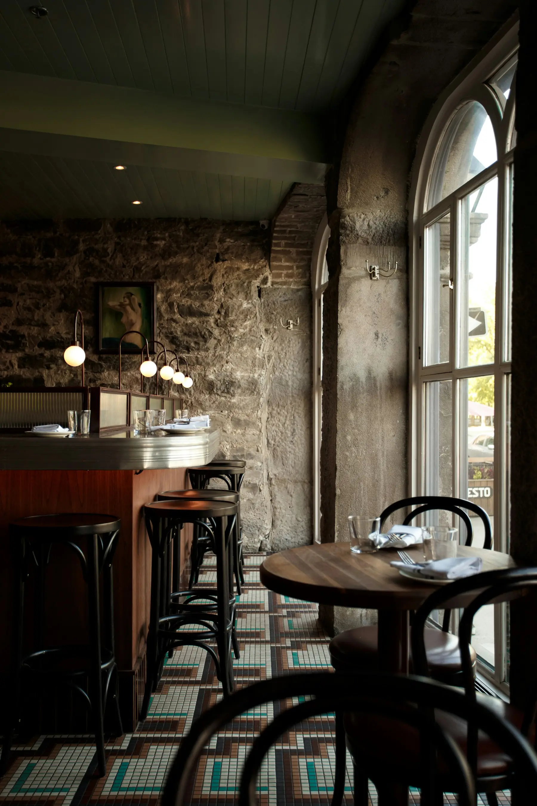Le comptoir et la salle du bistrot, avec ses tabourets et ses tables en bois